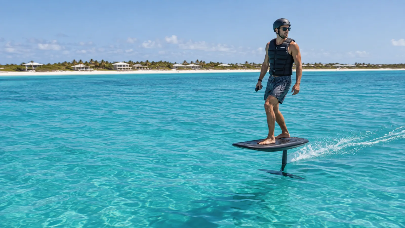 Rider in a vest and helmet flying an eFoil above turquoise water