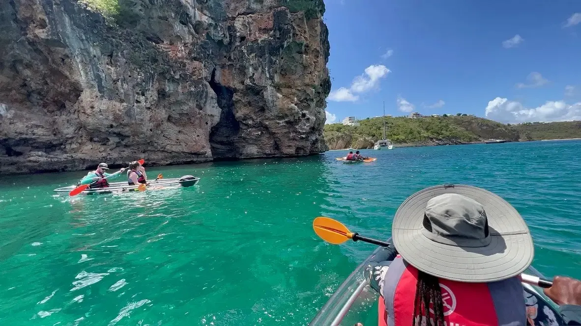 Clear kayaks on the emerald water of Crocus Bay beneath the cliffs