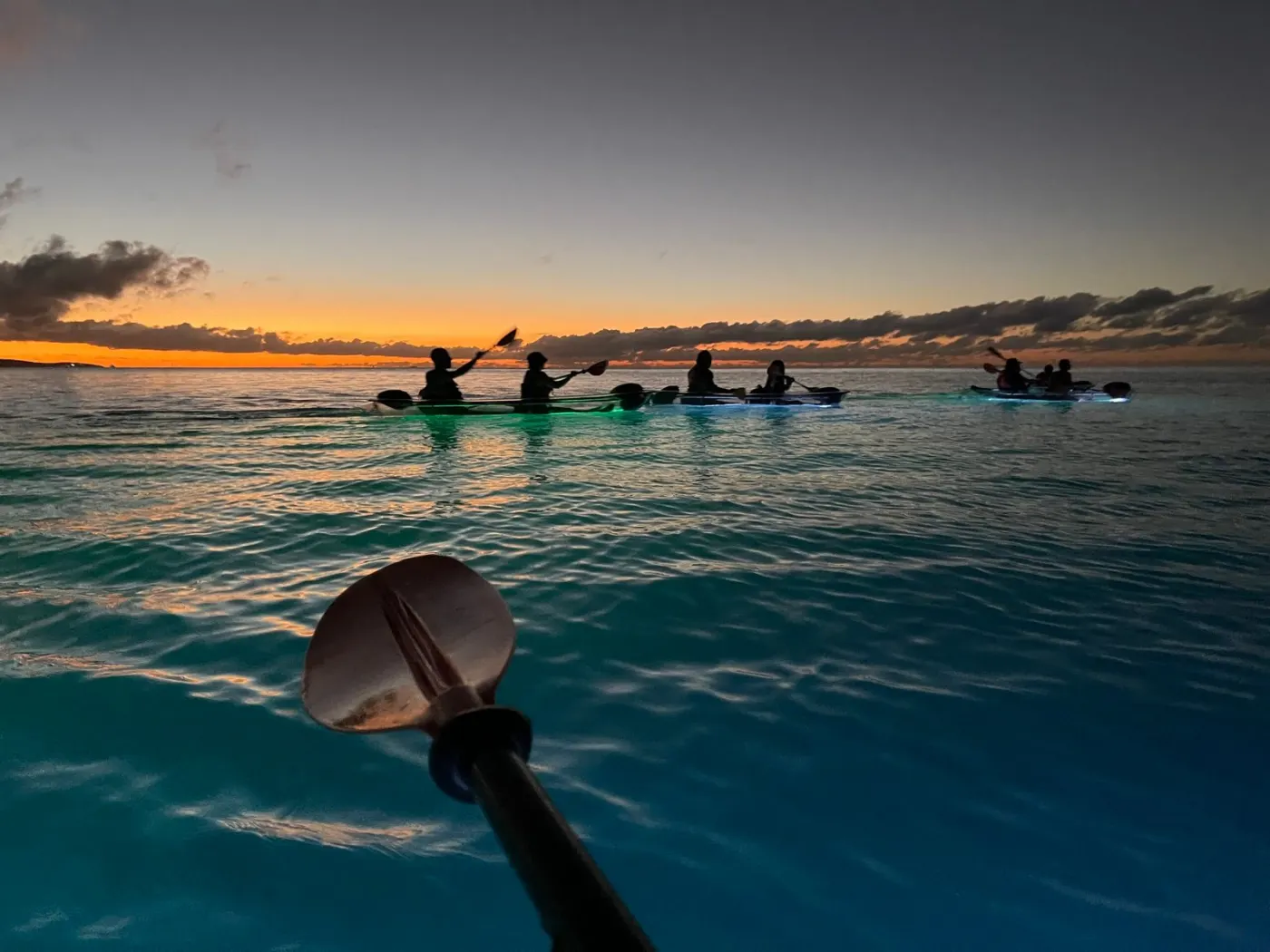 Clear kayaks paddling into the last of the sunset light