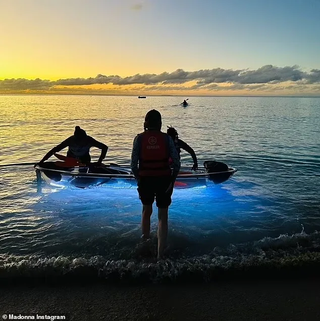 The family stepping into a glowing clear kayak at the shoreline at sunset