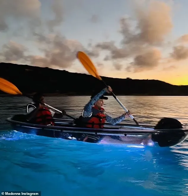 Madonna and family paddling an LED-lit clear kayak at dusk