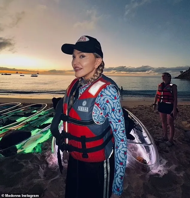 Madonna smiling on the beach at sunset with LED-lit clear kayaks behind her