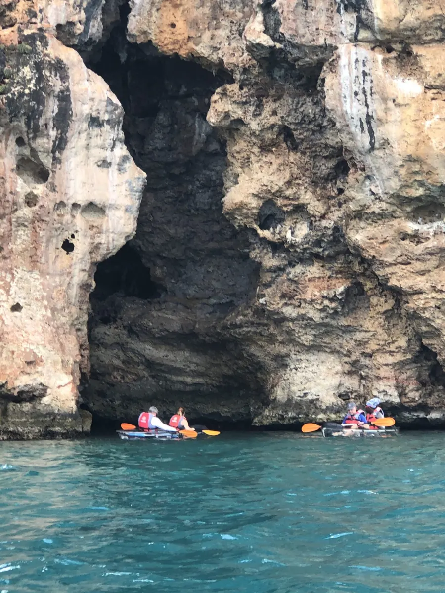 Two clear kayaks resting at the mouth of a sea cave